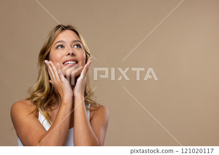 Caucasian woman wearing natural makeup and beige nail polish on beige background, copy space 121020117