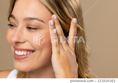 Caucasian woman wearing natural makeup and beige nail polish on beige background 121020163