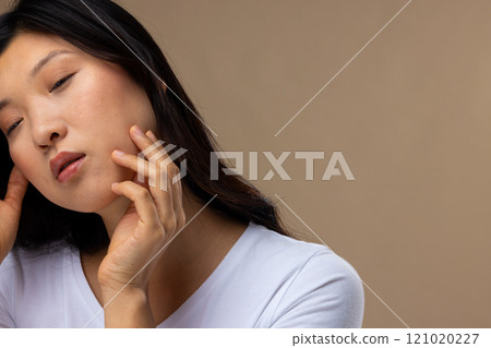 Asian woman wearing natural makeup and white t-shirt on beige background, copy space Asian woman wearing natural makeup and white t-shirt on beige background, copy space 121020227
