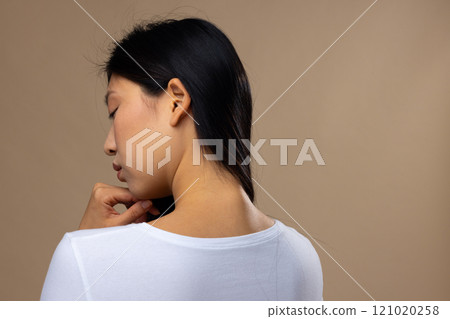 Asian woman wearing natural makeup and white t-shirt on beige background, copy space 121020258