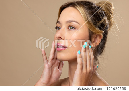 Caucasian woman wearing natural makeup and blue nail polish on beige background Caucasian woman wearing natural makeup and blue nail polish on beige background 121020268
