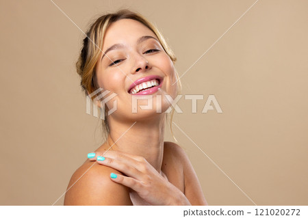 Portrait of caucasian woman wearing natural makeup and blue nail polish on beige background 121020272