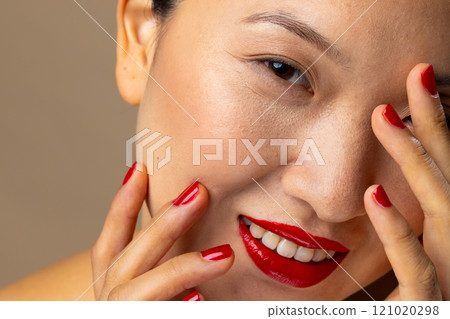 Portrait of asian woman wearing red lipstick and nail polish on beige background 121020298