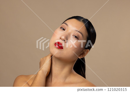 Portrait of asian woman wearing red lipstick and nail polish on beige background Portrait of asian woman wearing red lipstick and nail polish on beige background 121020315