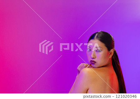 Asian woman wearing blue eyeliner and red nail polish on purple background, copy space 121020346
