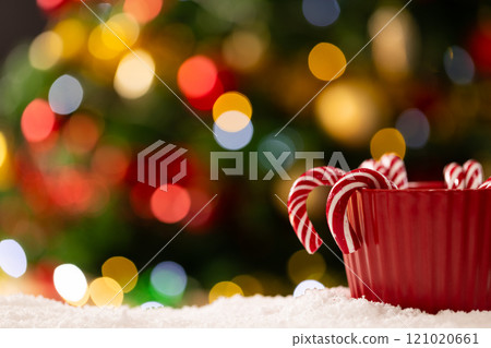 Mug with candy canes and christmas tree with fairy lights and copy space Mug with candy canes and christmas tree with fairy lights and copy space 121020661