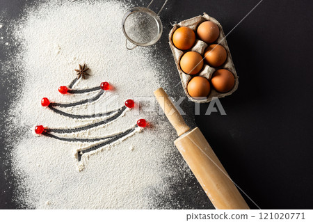 Anis seed and christmas tree shape in flour, eggs, roller with copy space on black background Anis seed and christmas tree shape in flour, eggs, roller with copy space on black background 121020771