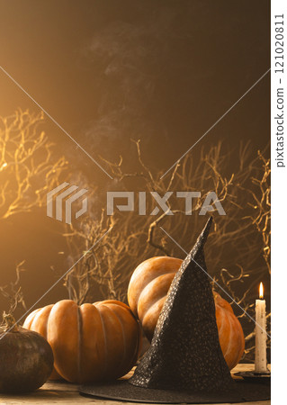 Vertical image of pumpkins and witch hat and burning candle with copy space on orange background Vertical image of pumpkins and witch hat and burning candle with copy space on orange background 121020811