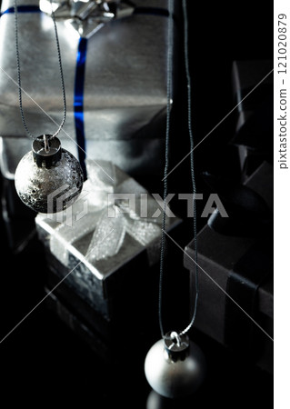 Vertical image of silver christmas baubles and gifts with copy space on black background 121020879