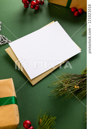 Vertical image of christmas decorations and white card with copy space on green background 121021016