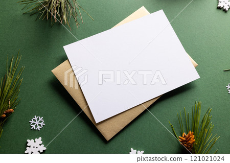 Christmas decorations with white card and copy space on green background 121021024