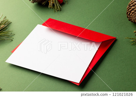 Christmas decorations with white card and copy space on green background 121021026