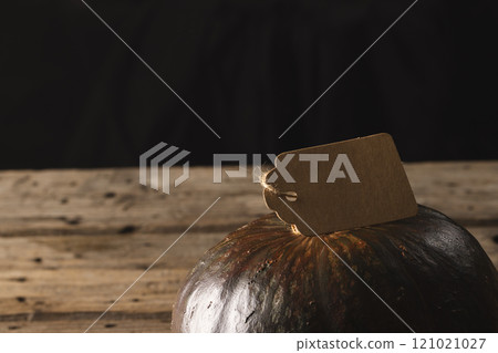 Pumpkin with tag with copy space on black and brown background 121021027