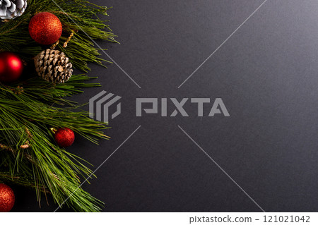 Christmas red baubles, fir tree and candy canes with copy space on black background 121021042