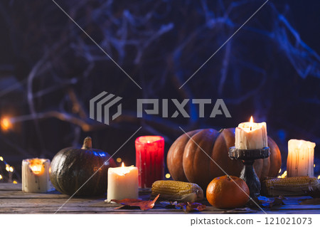 Pumpkins, oranges, corn cobs and candles with copy space on dark background 121021073
