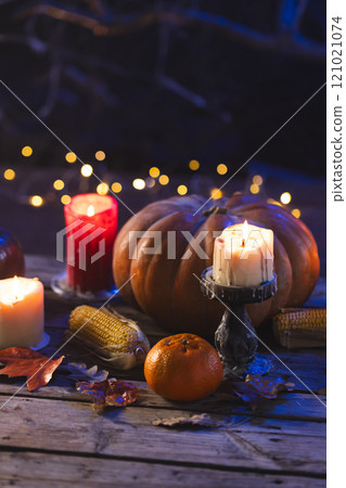 Vertical image of pumpkins, oranges, corn cobs and candles with copy space on dark background 121021074