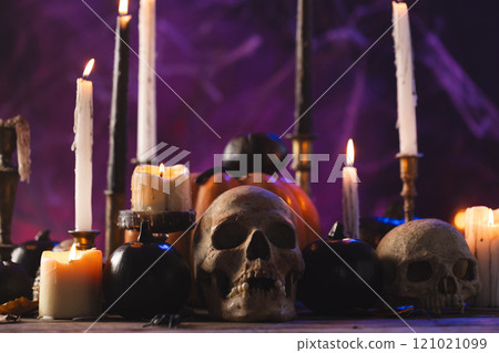 Pumpkins, skulls and burning candles on purple background Pumpkins, skulls and burning candles on purple background 121021099