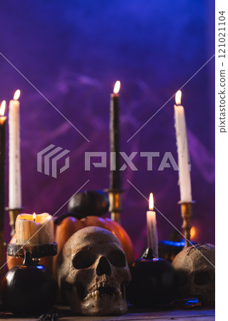 Vertical image of pumpkins, skulls and candles with copy space on purple background 121021104