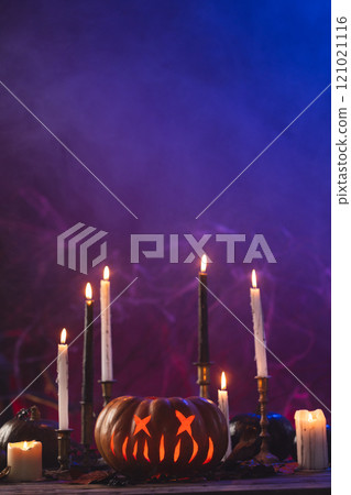 Vertical image of pumpkins and candles with copy space on purple background Vertical image of pumpkins and candles with copy space on purple background 121021116