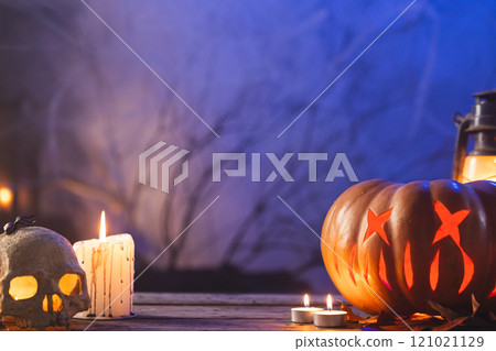 Carved pumpkin, skull and candle with copy space on blue background Carved pumpkin, skull and candle with copy space on blue background 121021129