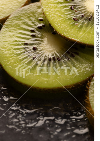 Micro close up of sliced kiwi fruits with water drops and copy space on black background 121021412