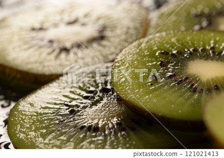 Micro close up of sliced kiwi fruits with water drops and copy space on black background Micro close up of sliced kiwi fruits with water drops and copy space on black background 121021413