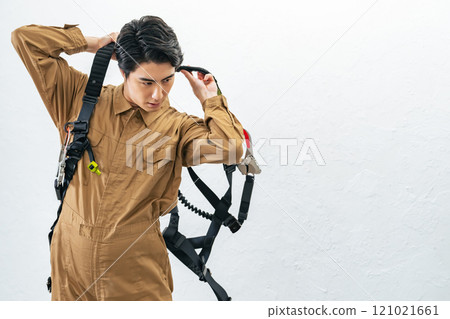 A male worker wearing a full harness for working at height A male worker wearing a full harness for working at height 121021661