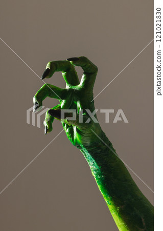 Vertical image of green monster hand with black nails making gesture on grey background Vertical image of green monster hand with black nails making gesture on grey background 121021830