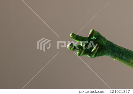Green monster hand with black nails making gesture on grey background 121021837