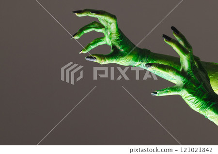 Green monster hands with black nails reaching on grey background 121021842