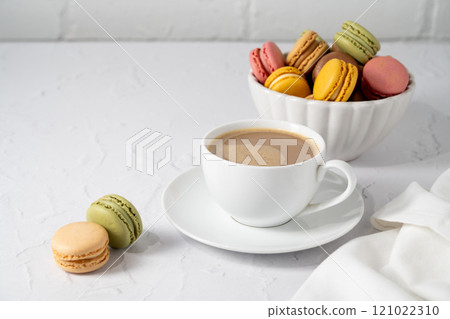 Macarons cookies with cup of coffee, stack of french macarons in a plate. Sweet dessert 121022310
