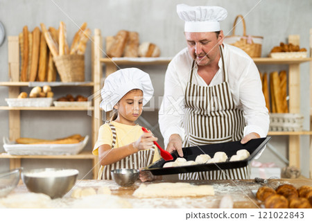 Daughter helps father baker to make pastries, lubricate croissants with loosened egg 121022843