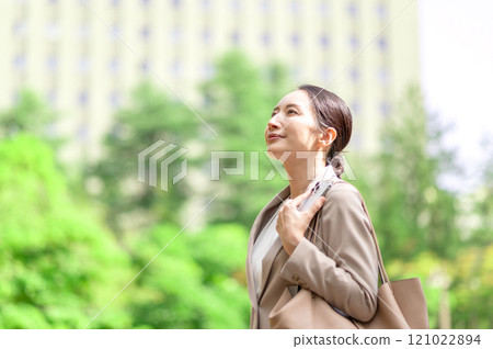Woman looking up while walking outdoors in fresh greenery Woman looking up while walking outdoors in fresh greenery 121022894