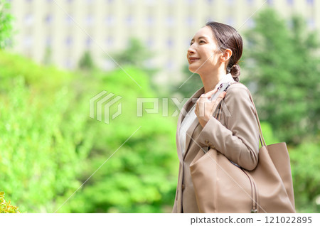 Woman looking up while walking outdoors in fresh greenery Woman looking up while walking outdoors in fresh greenery 121022895