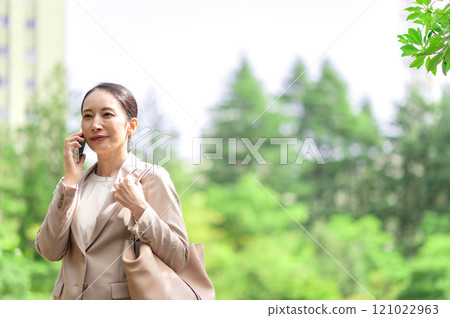 A businesswoman talking on a smartphone while walking 121022963