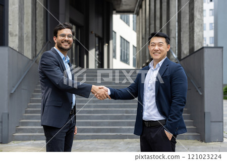Two business professionals in formal attire exchange a confident handshake outside a modern office. The image captures a moment of agreement and partnership, symbolizing connection and success. Two business professionals in formal attire exchange a confident handshake outside a modern office. The image captures a moment of agreement and partnership, symbolizing connection and success. 121023224