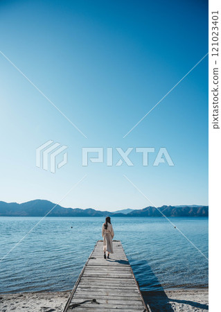 藍天下站在湖邊的年輕女子 121023401