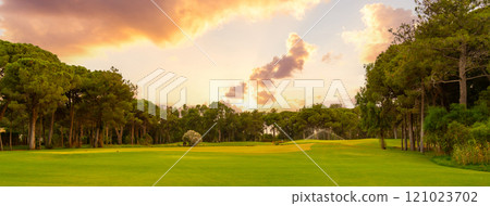 A lush golf course surrounded by trees, bathed in the golden hues of a serene sunset, offering a tranquil outdoor escape. A lush golf course surrounded by trees, bathed in the golden hues of a serene sunset, offering a tranquil outdoor escape. 121023702