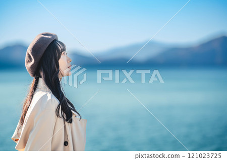 藍天下戴著貝雷帽和風衣的年輕女子 藍天下戴著貝雷帽和風衣的年輕女子 121023725