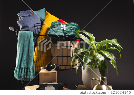 Shopping trolley with shopping, boxes, plant and copy space over black background 121024140