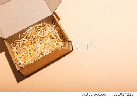 Open box with straw lining and copy space over cream background Open box with straw lining and copy space over cream background 121024226