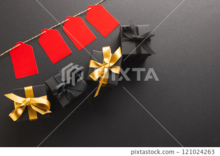 Red gift tags on pegs and black gift boxes with copy space over black background 121024263