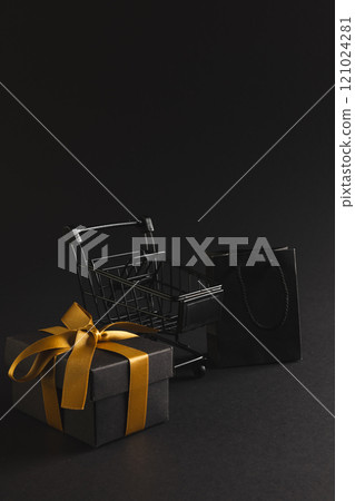 Vertical image of gift box with ribbon, gift bag, shopping trolley, copy space over black background Vertical image of gift box with ribbon, gift bag, shopping trolley, copy space over black background 121024281