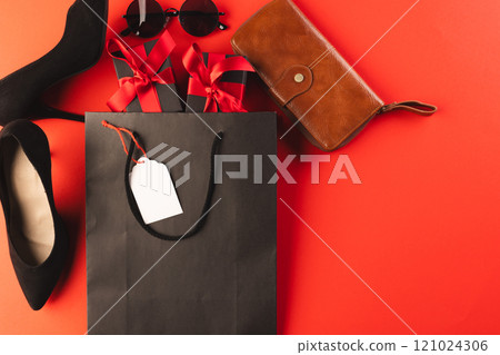 Gift bag, gift boxes, shoes, wallet, sunglasses and copy space over red background 121024306