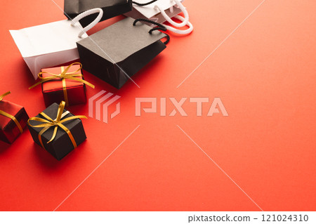 Gift boxes with ribbon, gift bags with copy space over red background Gift boxes with ribbon, gift bags with copy space over red background 121024310