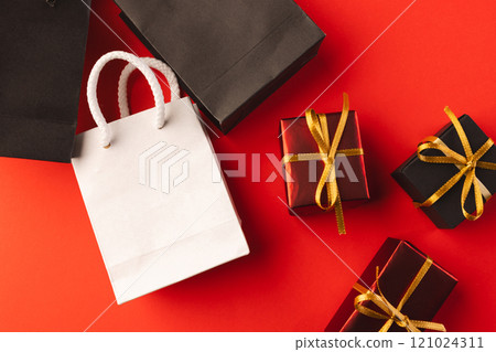 Gift boxes with ribbon, gift bags with copy space over red background Gift boxes with ribbon, gift bags with copy space over red background 121024311