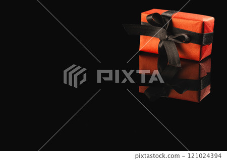 Red gift box with ribbon and copy space over black background Red gift box with ribbon and copy space over black background 121024394