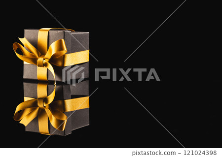 Black gift box with ribbon and copy space over black background 121024398