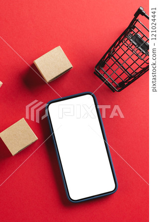 Vertical image of smartphone with copy space and trolley with boxes on red background 121024441