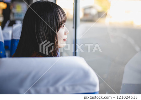Young woman on a bus looking out the window 121024513